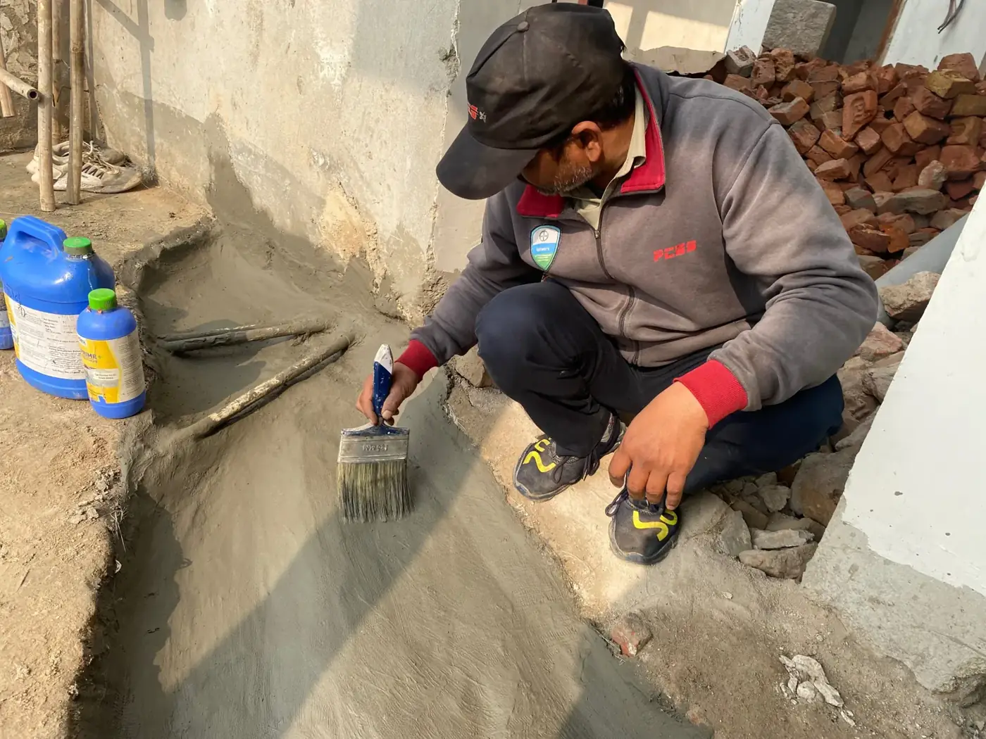 PCES applicator brushing waterproofing coat at a construction site
